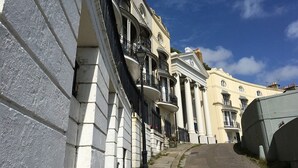 A street with classical architecture, including buildings with columns and balconies. - Moray Hastings (Hastings)