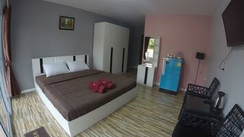 A hotel room with a bed, a desk, a refrigerator, and a television.