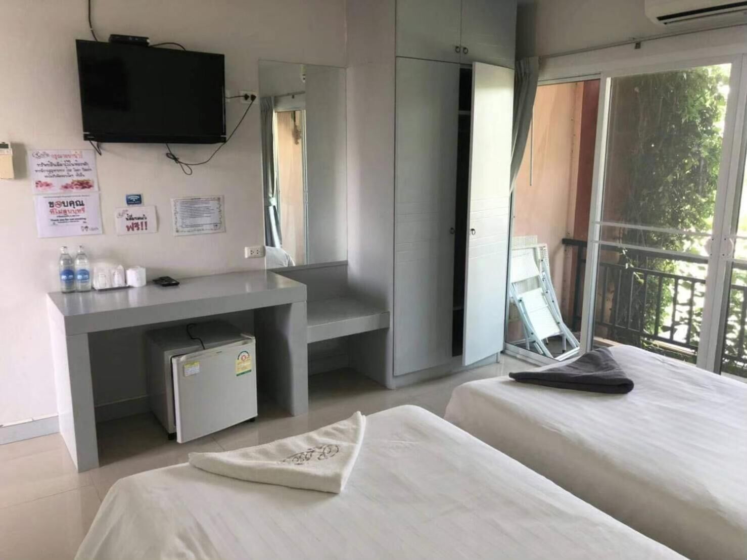 Ett hotellrum med en säng, ett skrivbord med en stol, en tv och ett fönster med utsikt över omgivningarna.