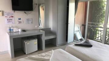Ett hotellrum med en säng, ett skrivbord med en stol, en tv och ett fönster med utsikt över omgivningarna.