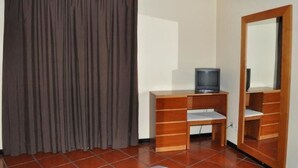 Ein Zimmer mit einem braunen Vorhang, einem Holz-Fernsehschrank und einem Spiegel an der Wand.