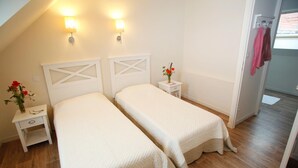 Ein Zimmer mit zwei Betten, einem Nachttisch mit Blumenvase und einer Wandlampe.