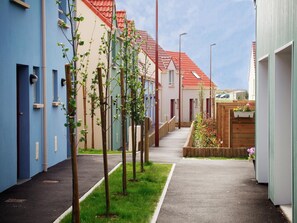 Eine Wohnstraße mit Häusern, Bürgersteig und jungen Bäumen.