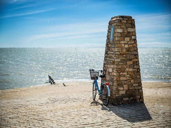 A stone monument by the beach with a bicycle parked nearby.