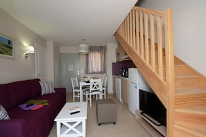A compact living space with a sofa, a dining table, chairs, a TV, and a kitchen area with a microwave and refrigerator. - Apartment in Le Paradou with Pool & Sauna (Paradou)