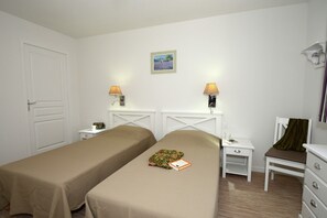A hotel room with two single beds, a small bedside table with a lamp, a chair, a dresser, and a painting on the wall. - Apartment in Le Paradou with Pool & Sauna (Paradou)