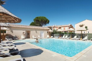 A swimming pool with lounge chairs and a thatched-roof structure. - Modern Stay with Pool & Terrace (AIGUES MORTES)