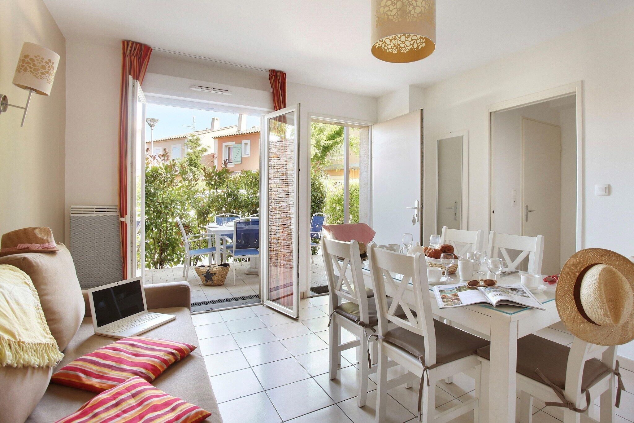 A modern living room with a sofa, a dining table with chairs, a laptop, and a dining set.