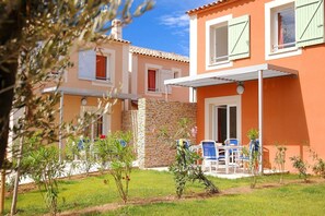 A two-story building with a stone wall and a covered patio area with outdoor seating. - Modern Stay with Pool & Terrace (AIGUES MORTES)