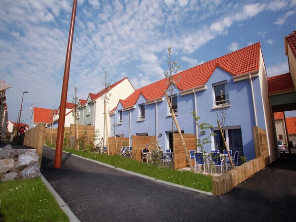 A row of modern houses with red-tiled roofs and a paved driveway.