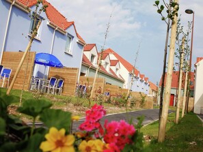 A row of houses with red-tiled roofs, wooden fences, and a blue umbrella.
