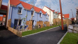 A row of residential buildings with red-tiled roofs and a paved driveway. - Relaxing Coastal Apt for 8 (le Crotoy)