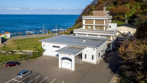 A coastal building with a parking lot, a road, and a view of the sea.