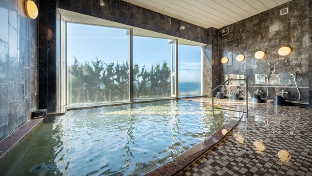 A modern indoor swimming pool with large windows, a tiled floor, and a water filtration system.