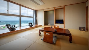 A modern room with tatami flooring, a wooden dining table, and a large window overlooking the ocean.