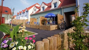 En rad hus med röda tegeltak och ett trästaket i förgrunden.