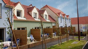 En rad moderna hus med röda tegeltak, trästaket och utomhusområden med sittplatser.