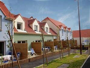 A row of modern houses with red-tiled roofs, wooden fences, and outdoor seating areas. - Spacious Coastal Apt w/ Garden (le Crotoy)