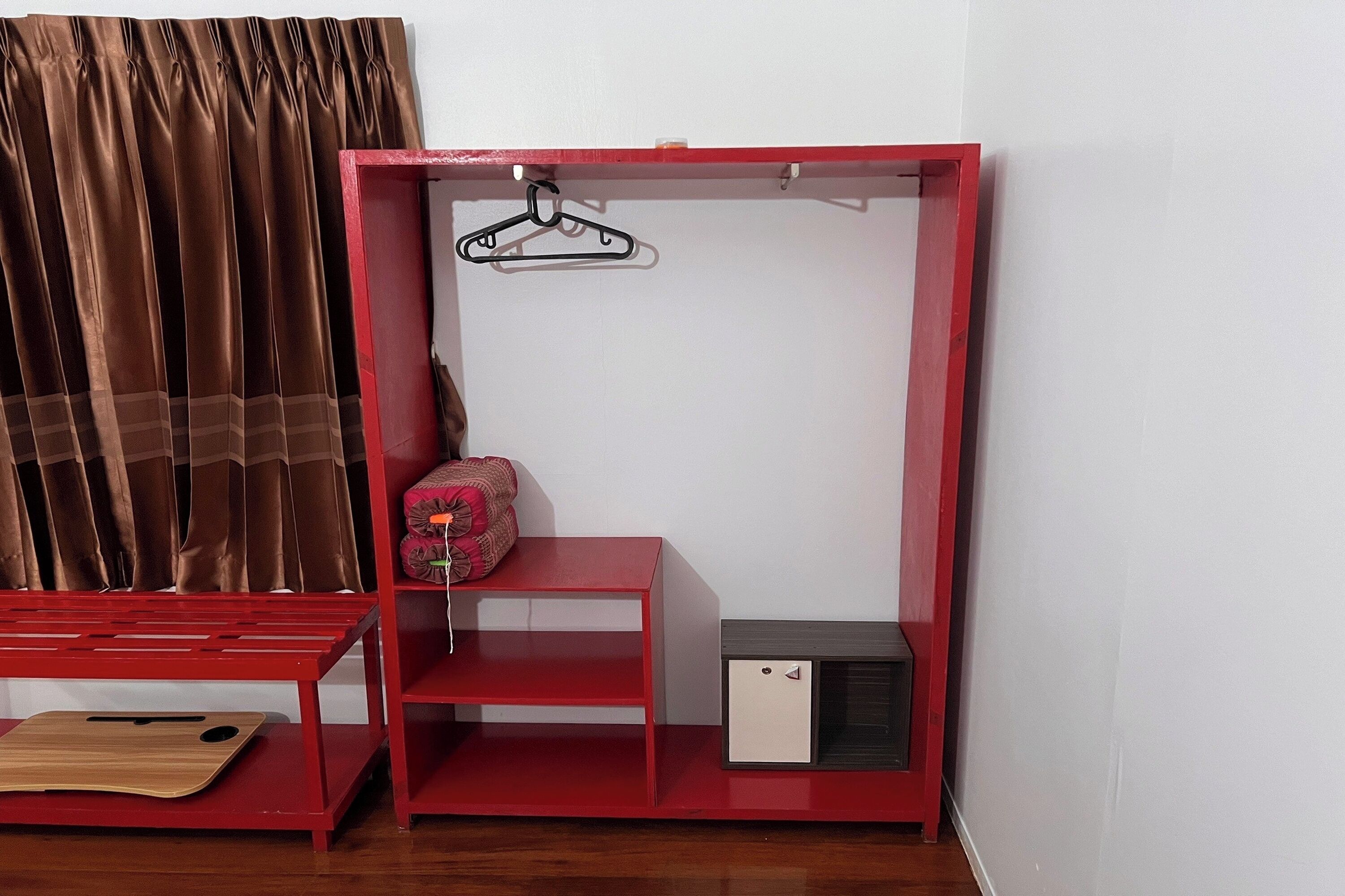 Un armario rojo con una barra para colgar, un estante pequeño y un compartimento.