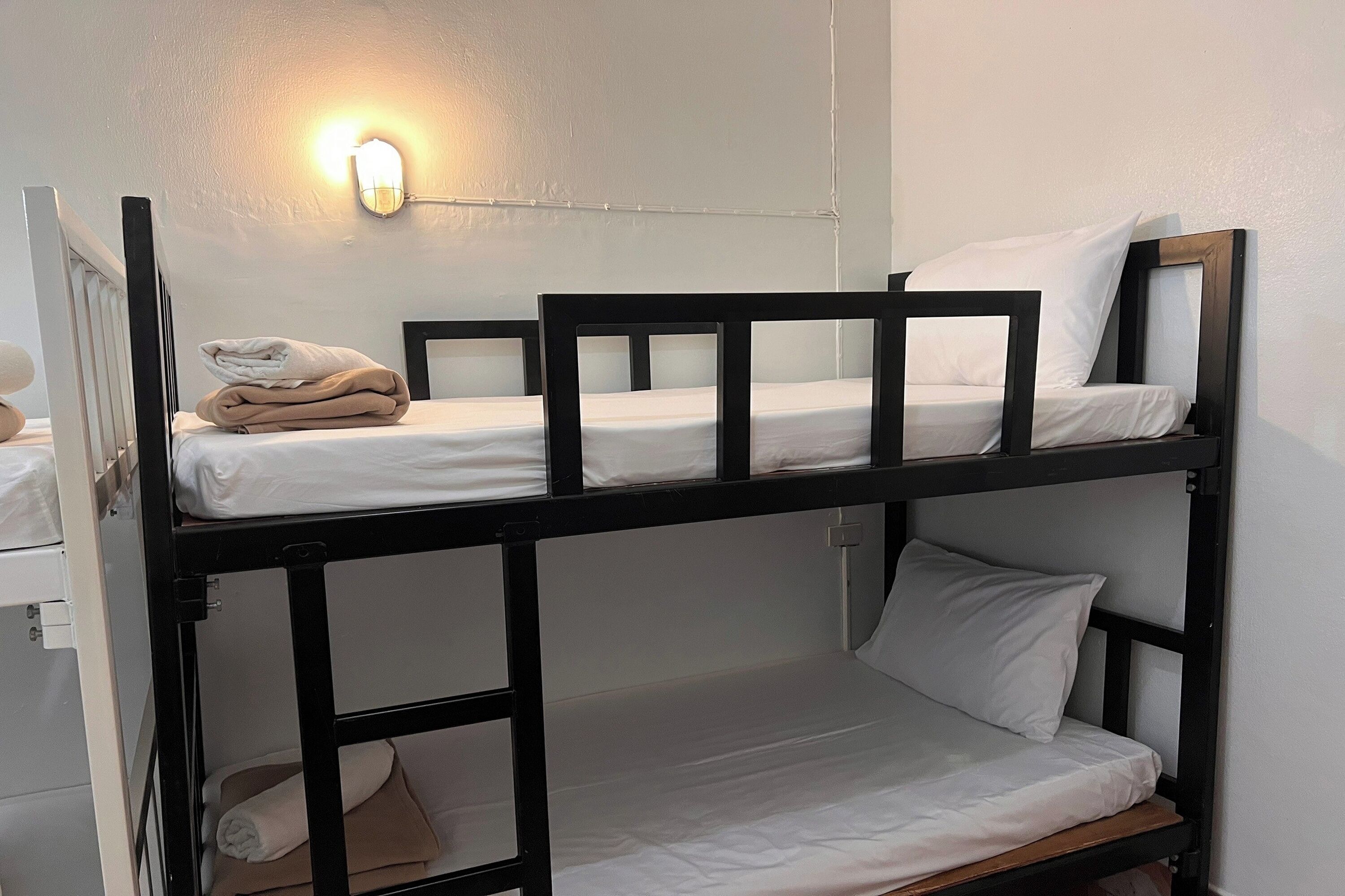 A bunk bed with white bedding and a wall-mounted light fixture.