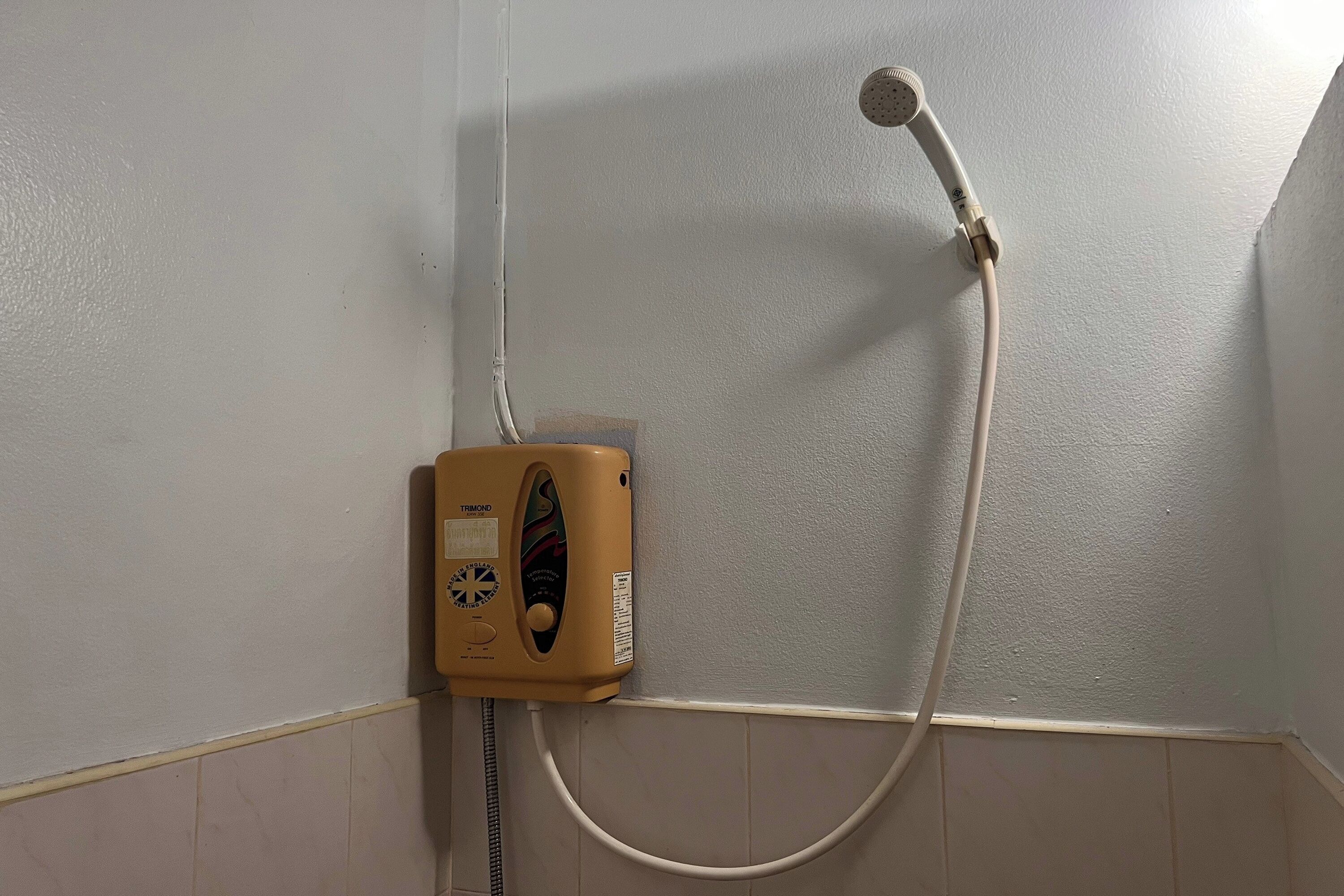 A shower unit with a hose and control panel in a corner of a room.
