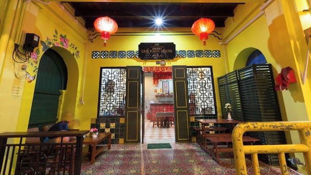 Interior de un restaurante chino tradicional, con zona central de comedor abierta, mesas y sillas.