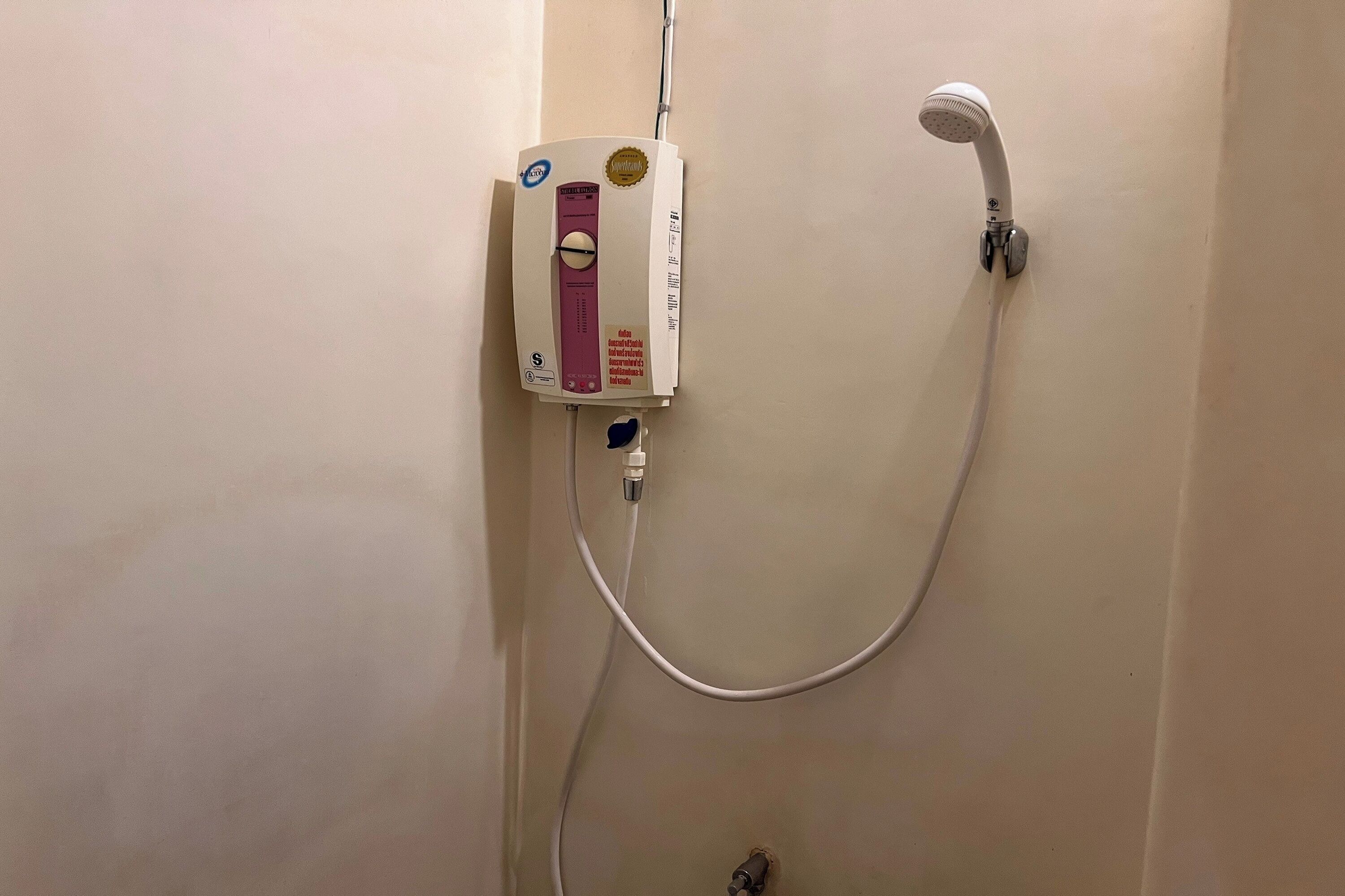 A shower with a handheld showerhead and a control panel.