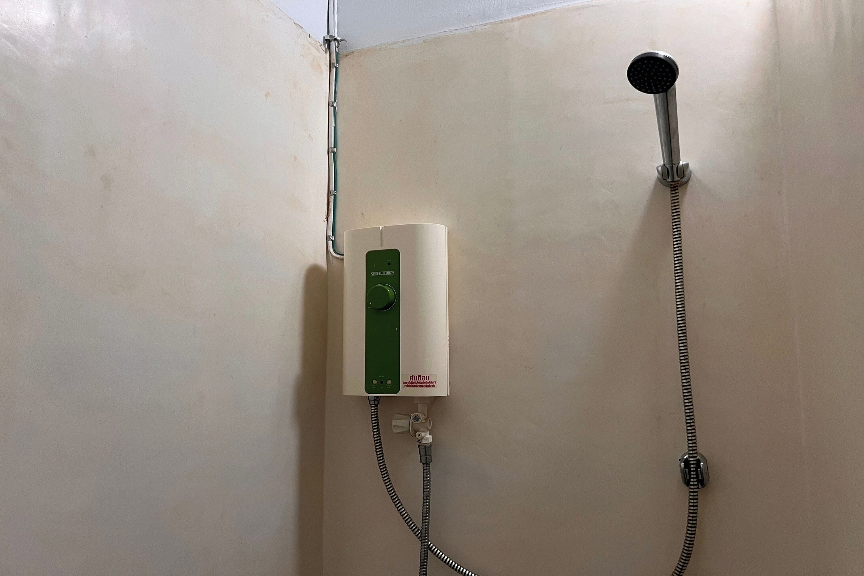 A shower with a handheld showerhead and a wall-mounted control panel.