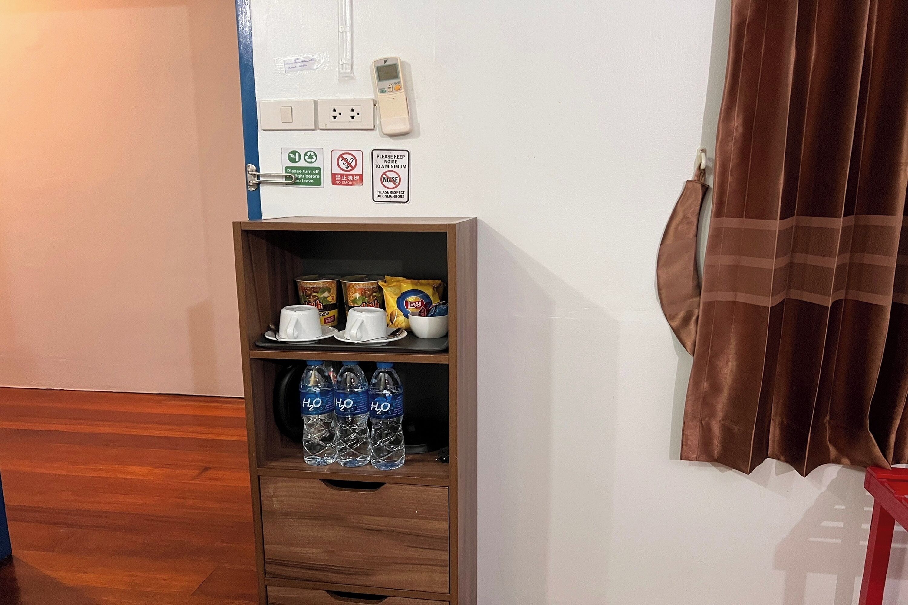A wooden shelf with cups, bowls, and bottled water.