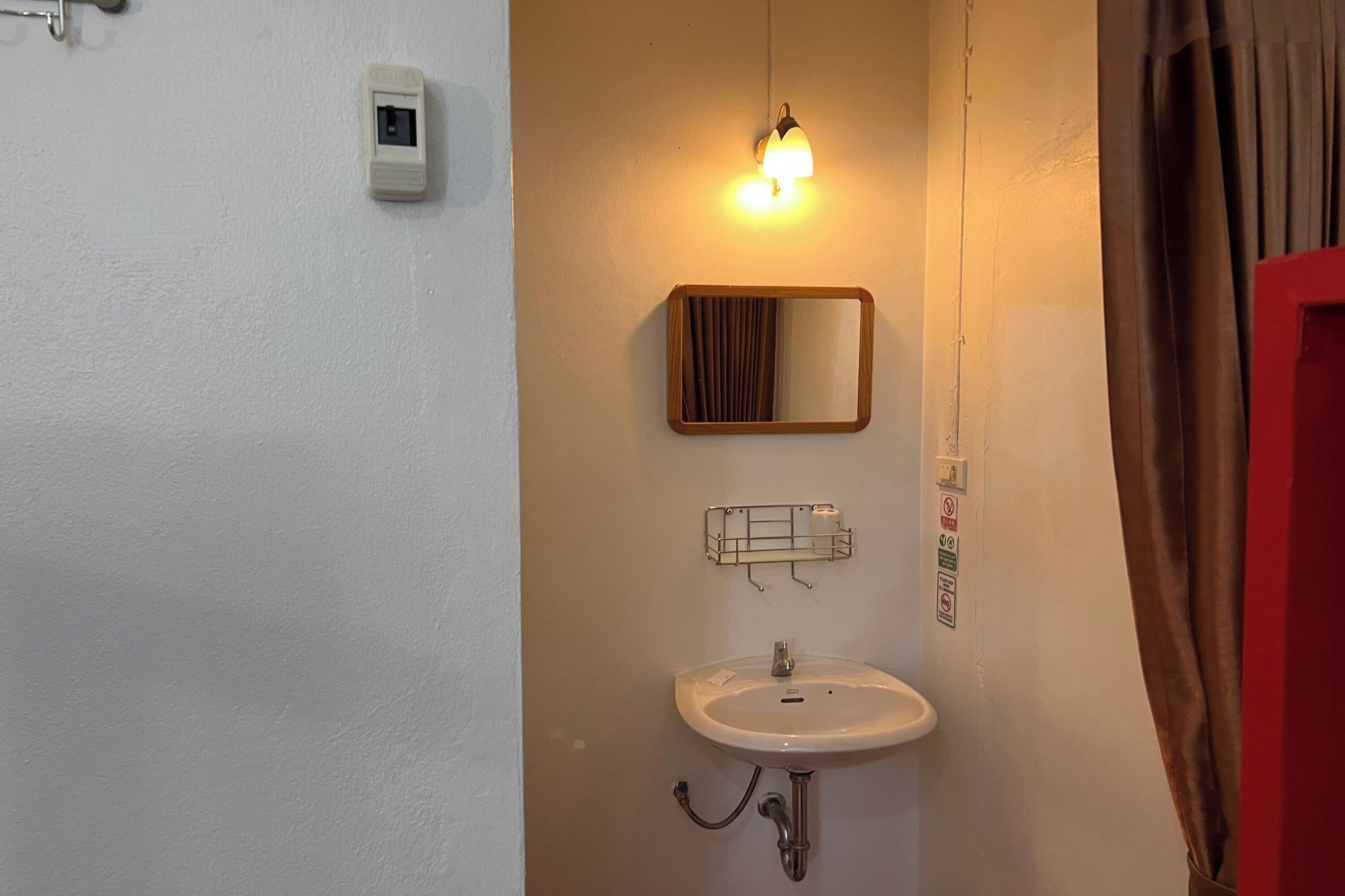 A bathroom with a white sink, a mirror, and a light fixture above the mirror.