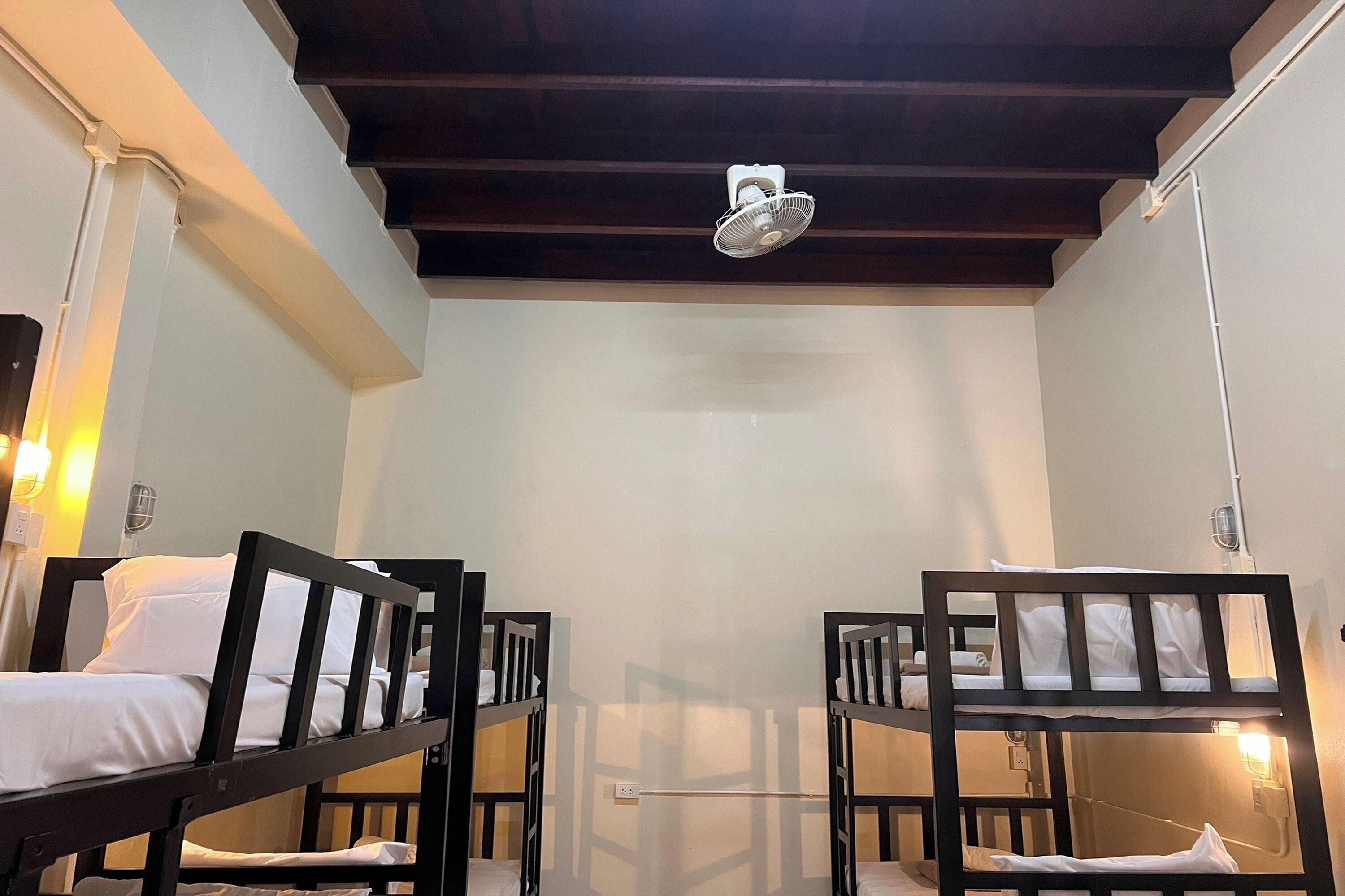 A room with bunk beds, a ceiling fan, and a light fixture.