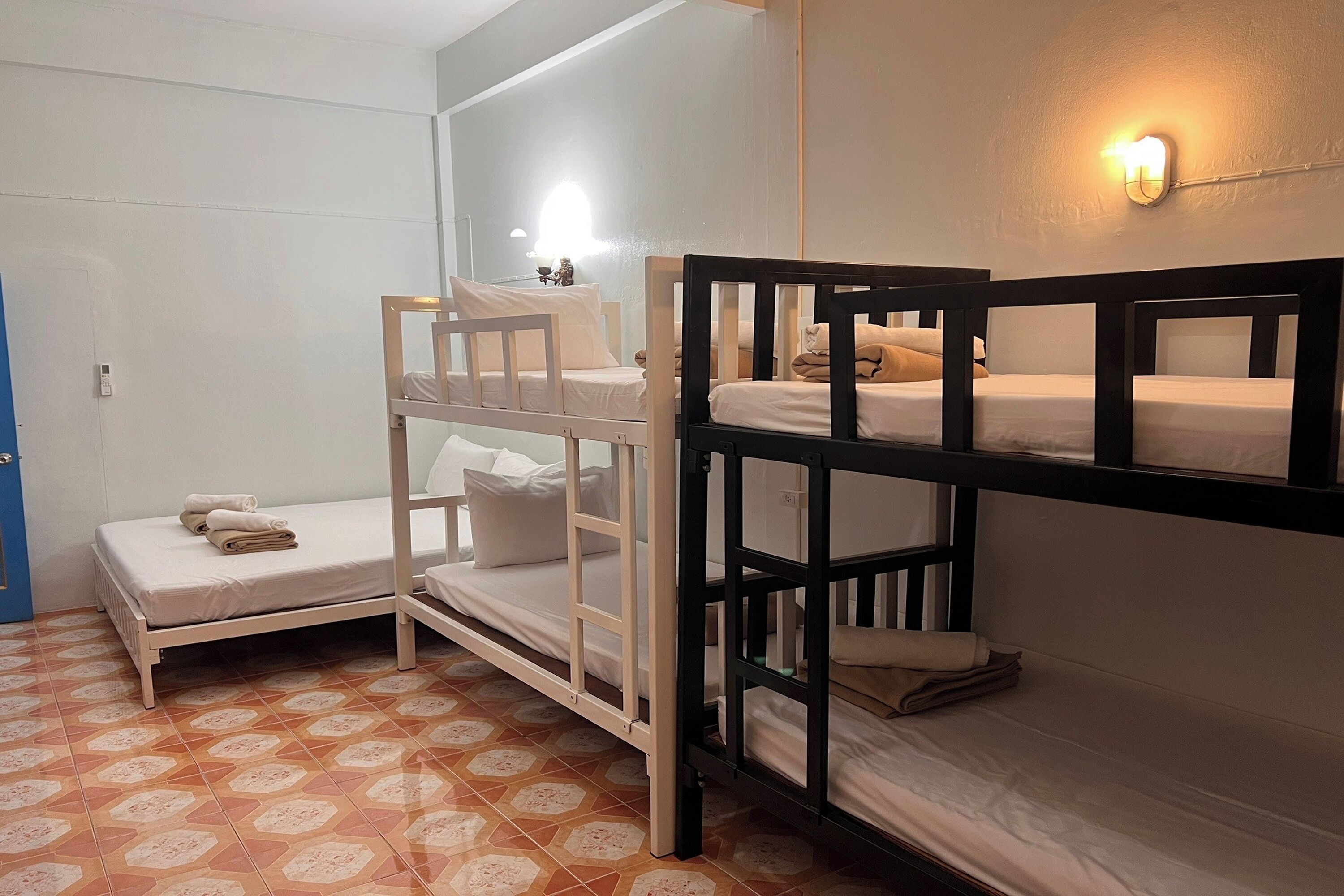 A room with bunk beds, a small bedside table, and a wall-mounted light fixture.