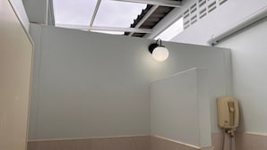 Un espacio de ducha con luz en el techo, un secador de manos y un tragaluz.