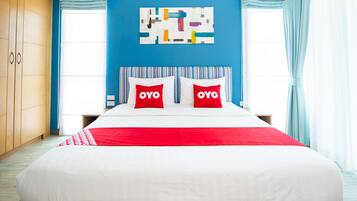 Un dormitorio con una cama grande, una pared de acento azul y una obra de arte abstracto sobre la cama.