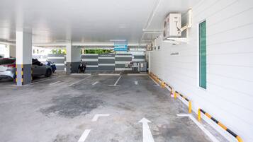 Un estacionamiento con flechas direccionales en el suelo, un letrero azul y una motocicleta estacionada cerca de la entrada.