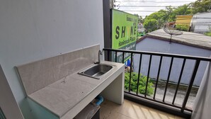 Un pequeño balcón con un lavabo, un cubo de basura y vistas a un cartel de hotel.