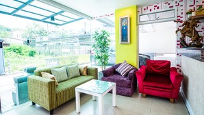 Una sala de estar moderna con un sofá verde, un sillón rojo y una mesa de centro de vidrio.