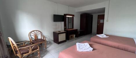 A hotel room with two beds, a desk, a chair, a wardrobe, and a mirror.