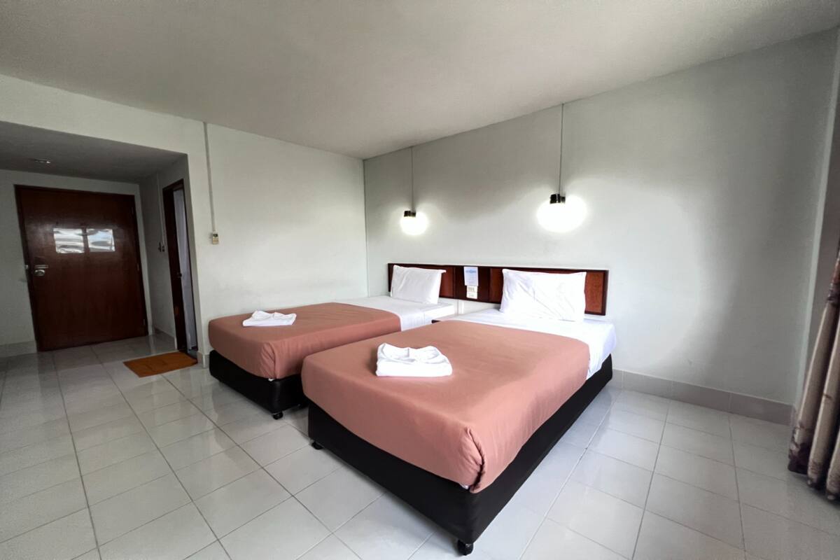 A hotel room with two beds, a wooden headboard, and a white door.