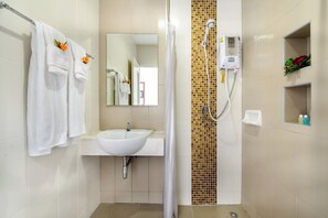 A bathroom with a white sink, a mirror, a shower with a control panel, and a towel rack with towels. - The Topaz Residence (Phuket)