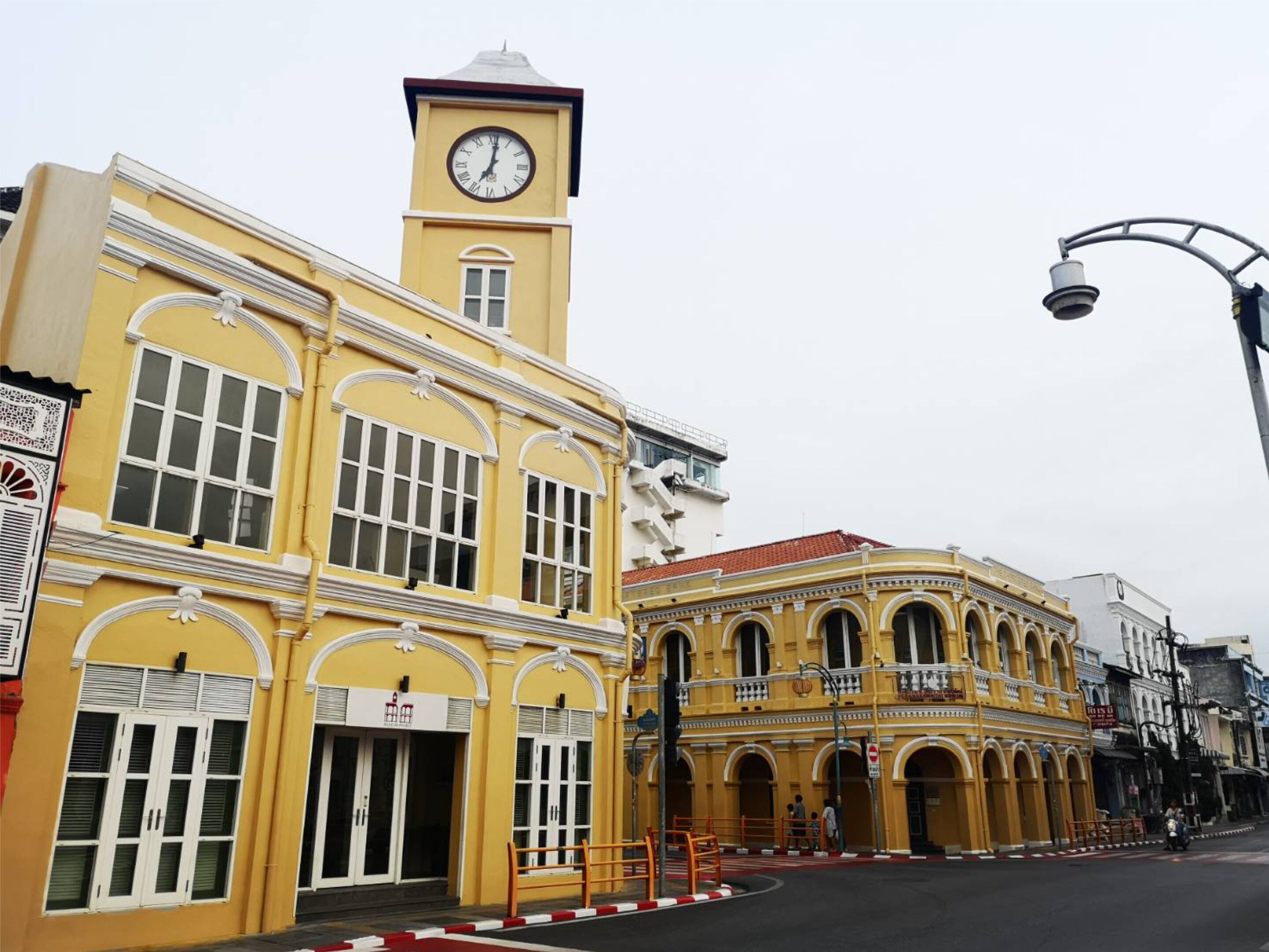 Un edificio amarillo con una torre de reloj, ventanas en arco y un balcón.