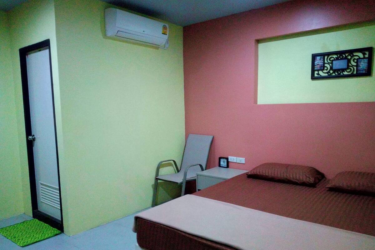 Un dormitorio con cama, escritorio, silla, aire acondicionado y puerta.