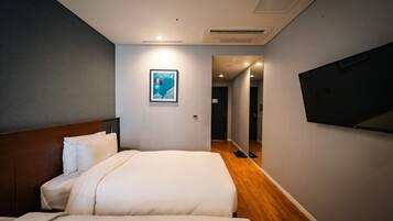 A hotel room with two beds, a mounted TV, and a framed picture on the wall.