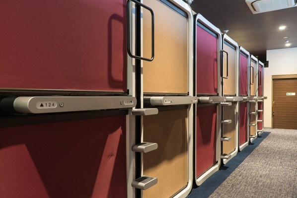 A row of bunk beds with individual compartments, each with a privacy curtain and a handle.