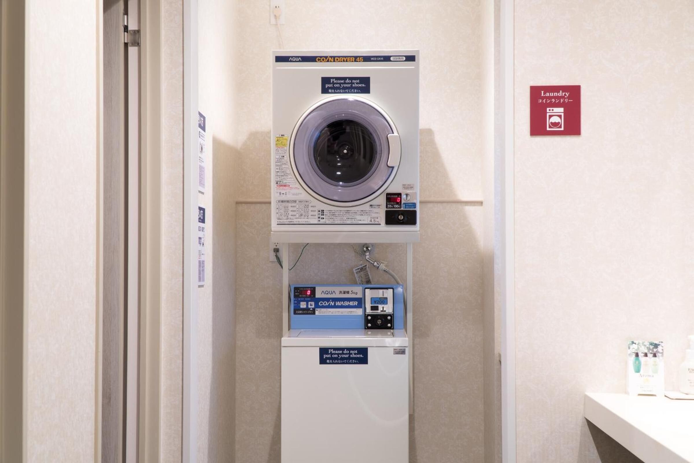 A laundry facility with a front-loading washer and dryer, a CO/N washer, and a sign indicating the location.