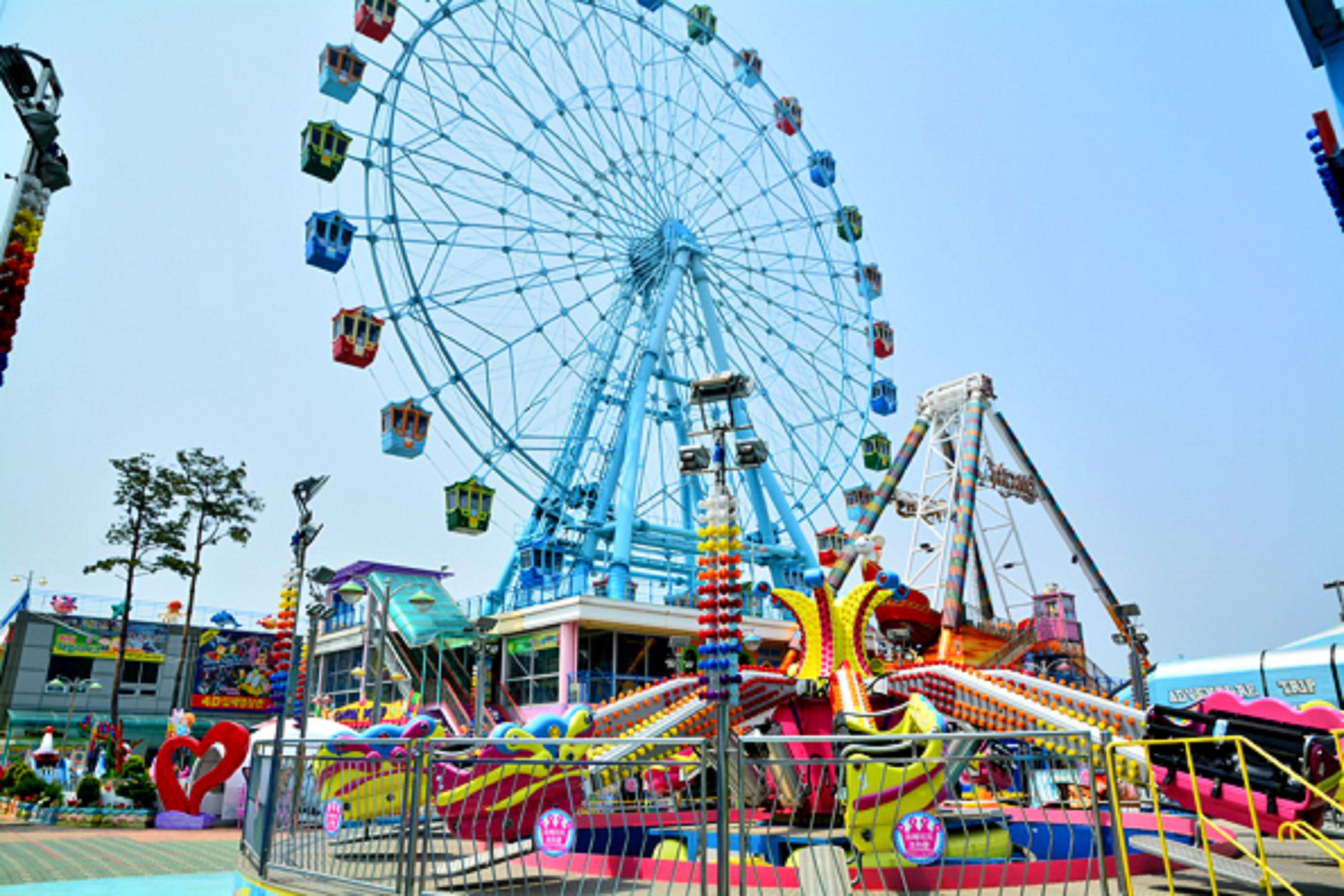 A Ferris wheel and various amusement rides at an outdoor fair.