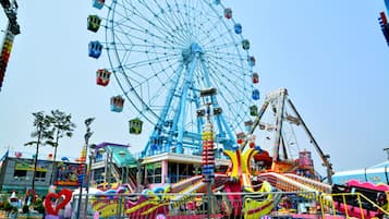 A Ferris wheel and various amusement rides at an outdoor fair.
