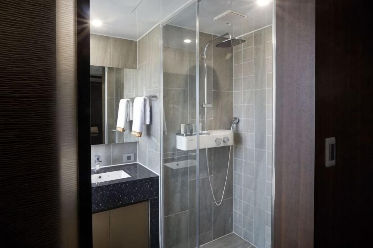 A modern bathroom with a glass-enclosed shower, a sink, and a mirror.
