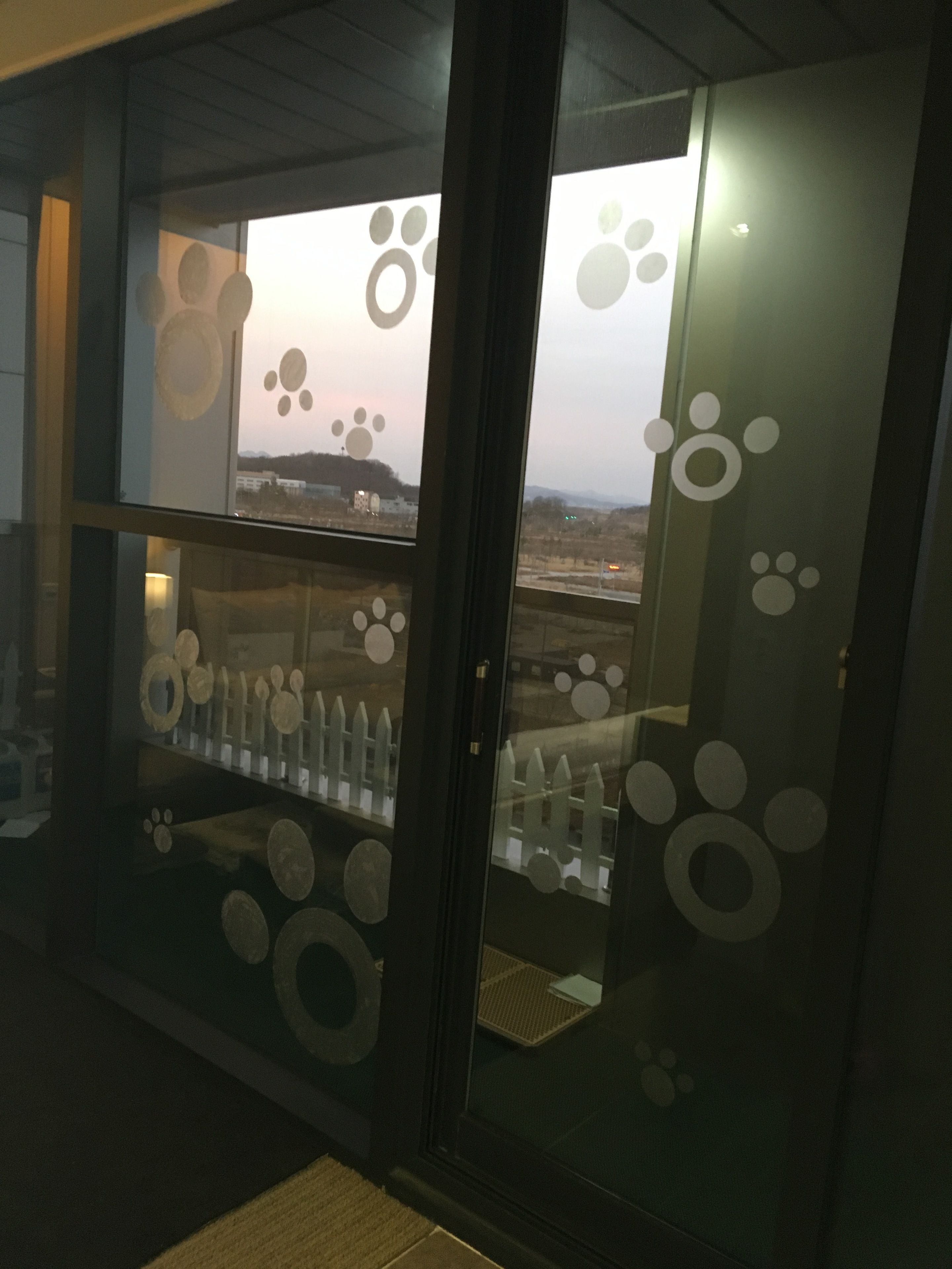 A room with a glass door featuring paw print decorations.