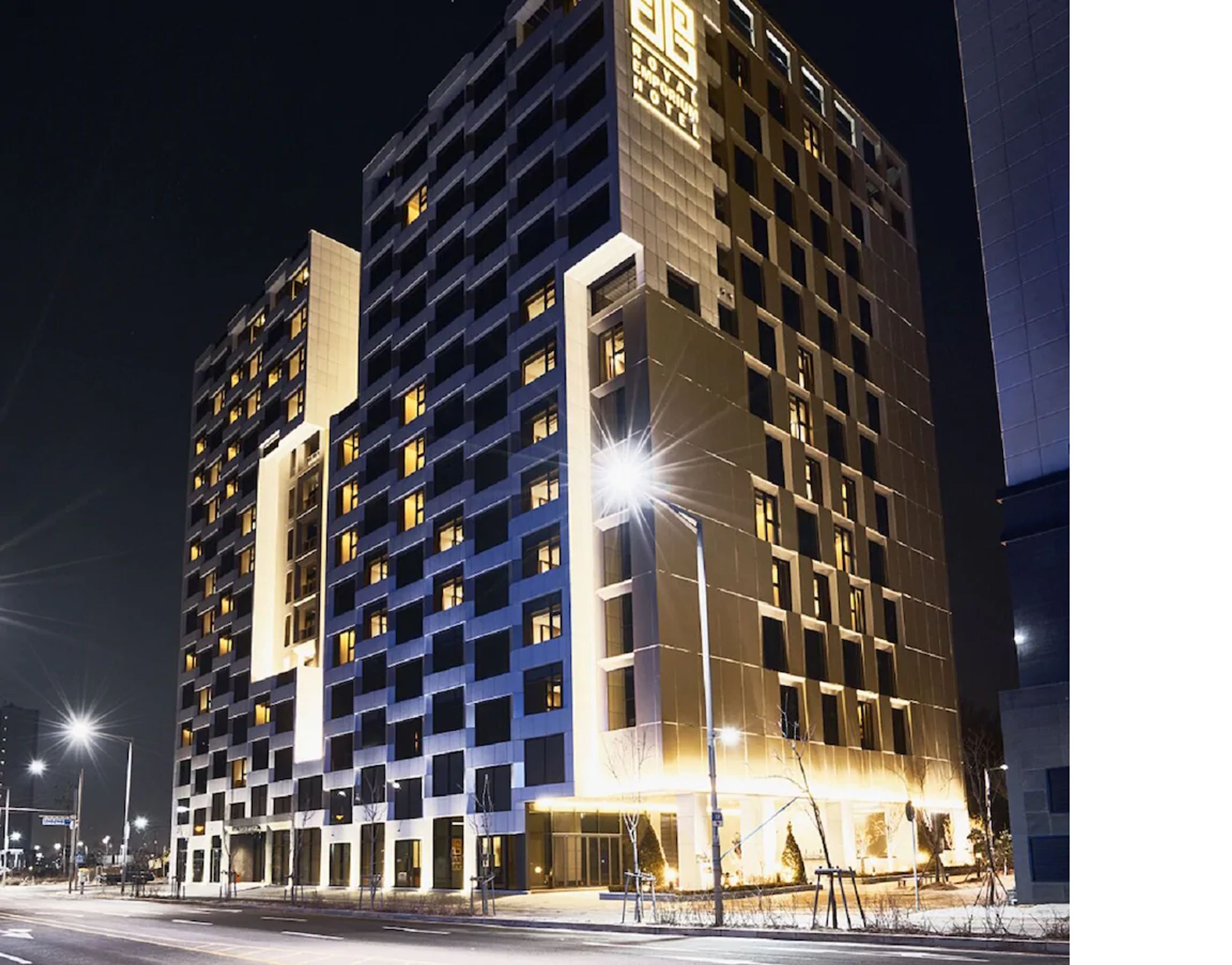 Een hotel met meerdere verdiepingen, met een modern design, een opvallende ingang en verlichte ramen.